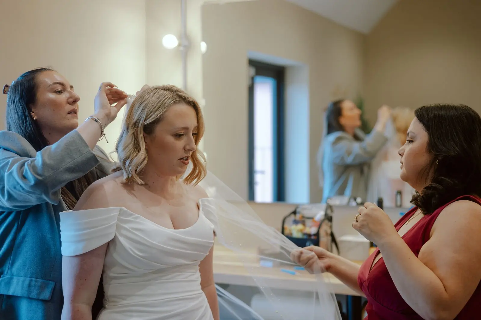 Bride having her veil fitted while her bridesmaids look on