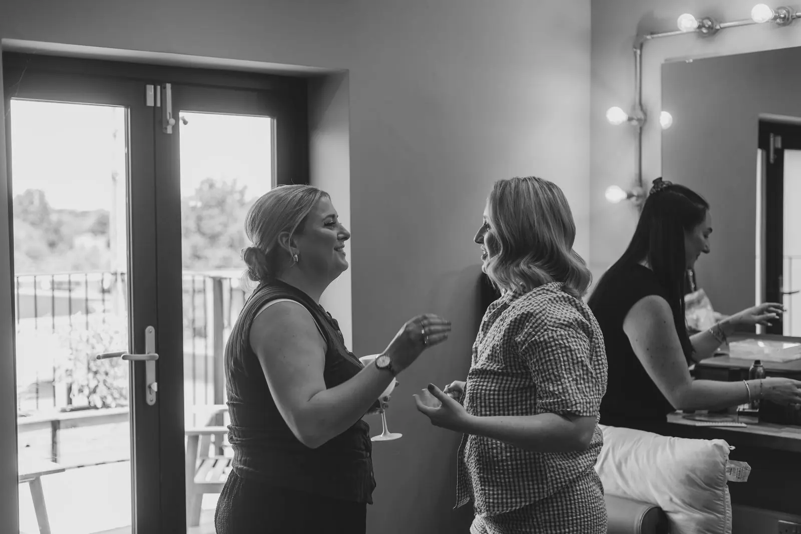 Bridesmaids chatting in front of the dressing mirror in black and white