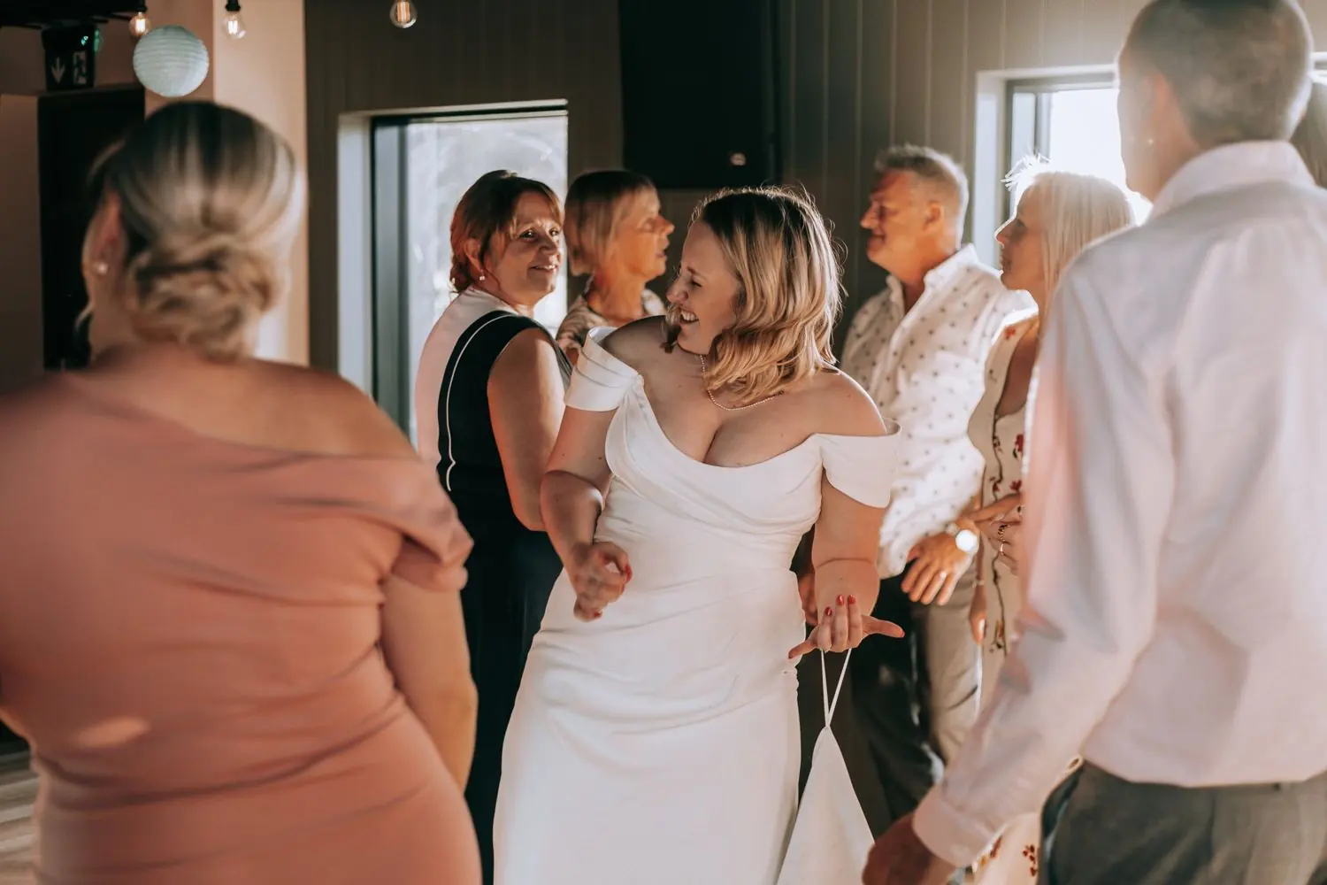 Bride laughing and dancing with guests during the wedding reception
