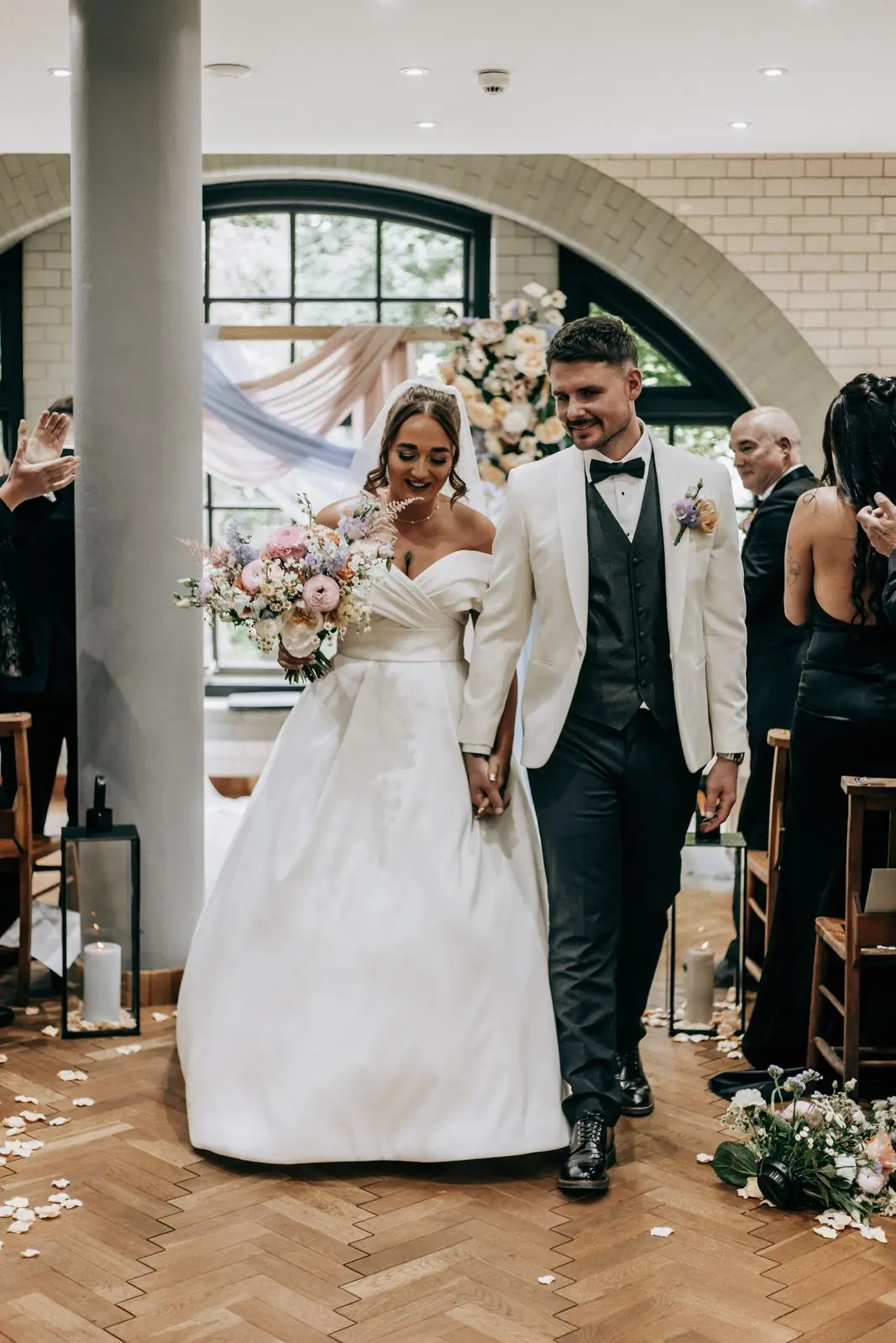 Newlyweds walking back down the aisle past flowers