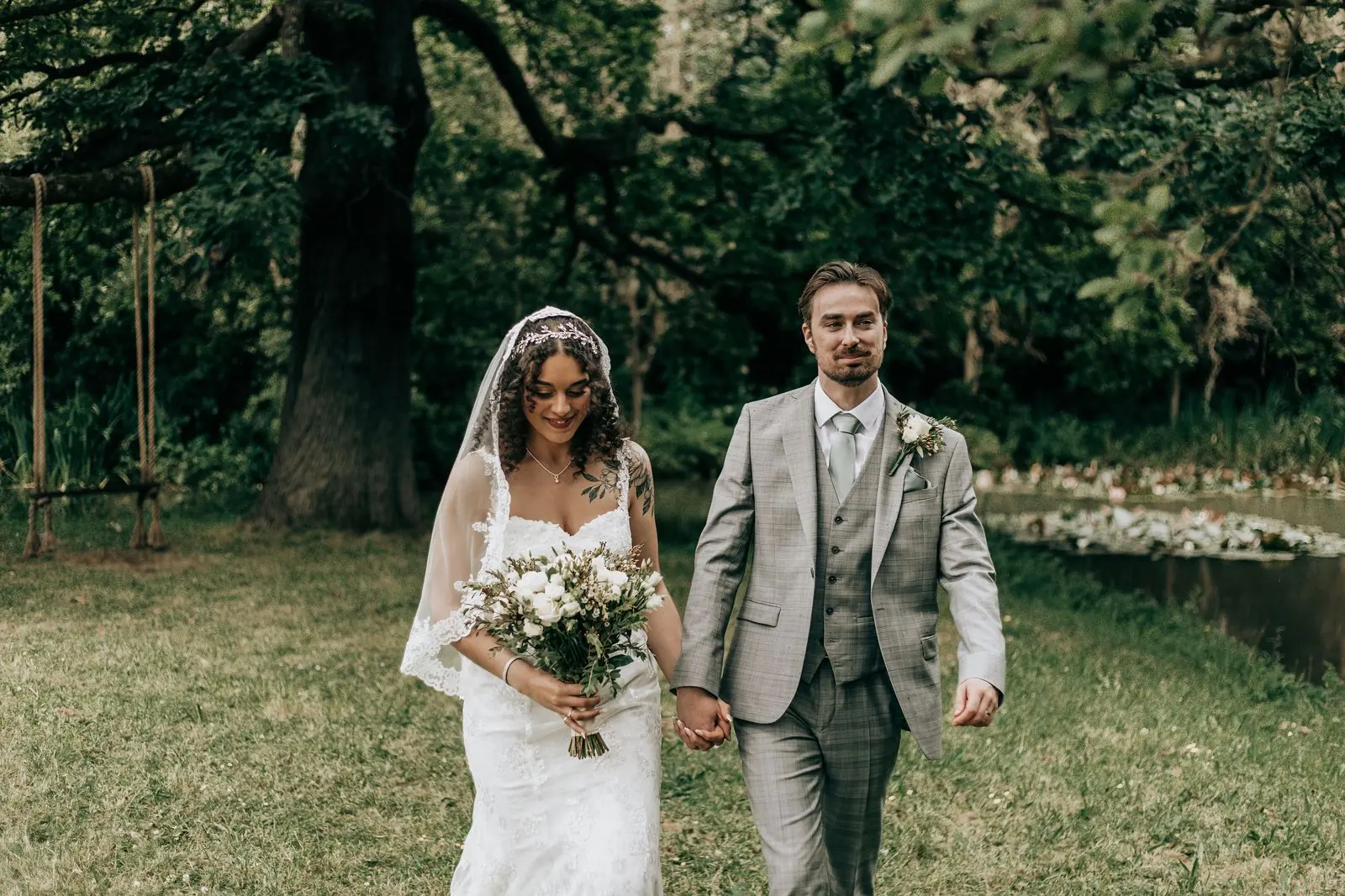 Bride and groom walking hand in hand across the lawn