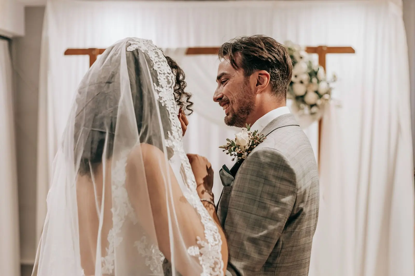 Groom looking at his bride through her veil