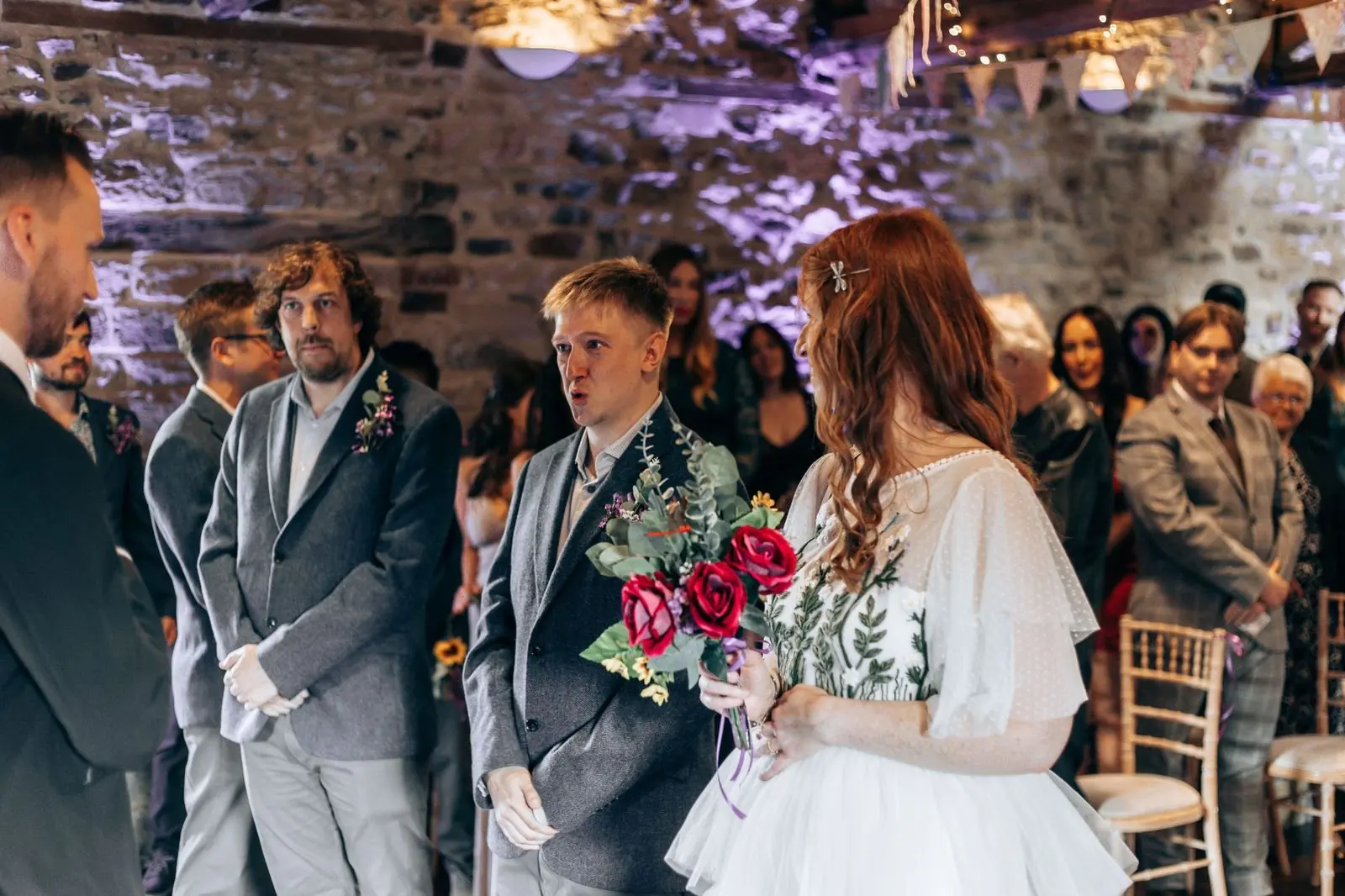 Couple at the front of the barn with guests watching