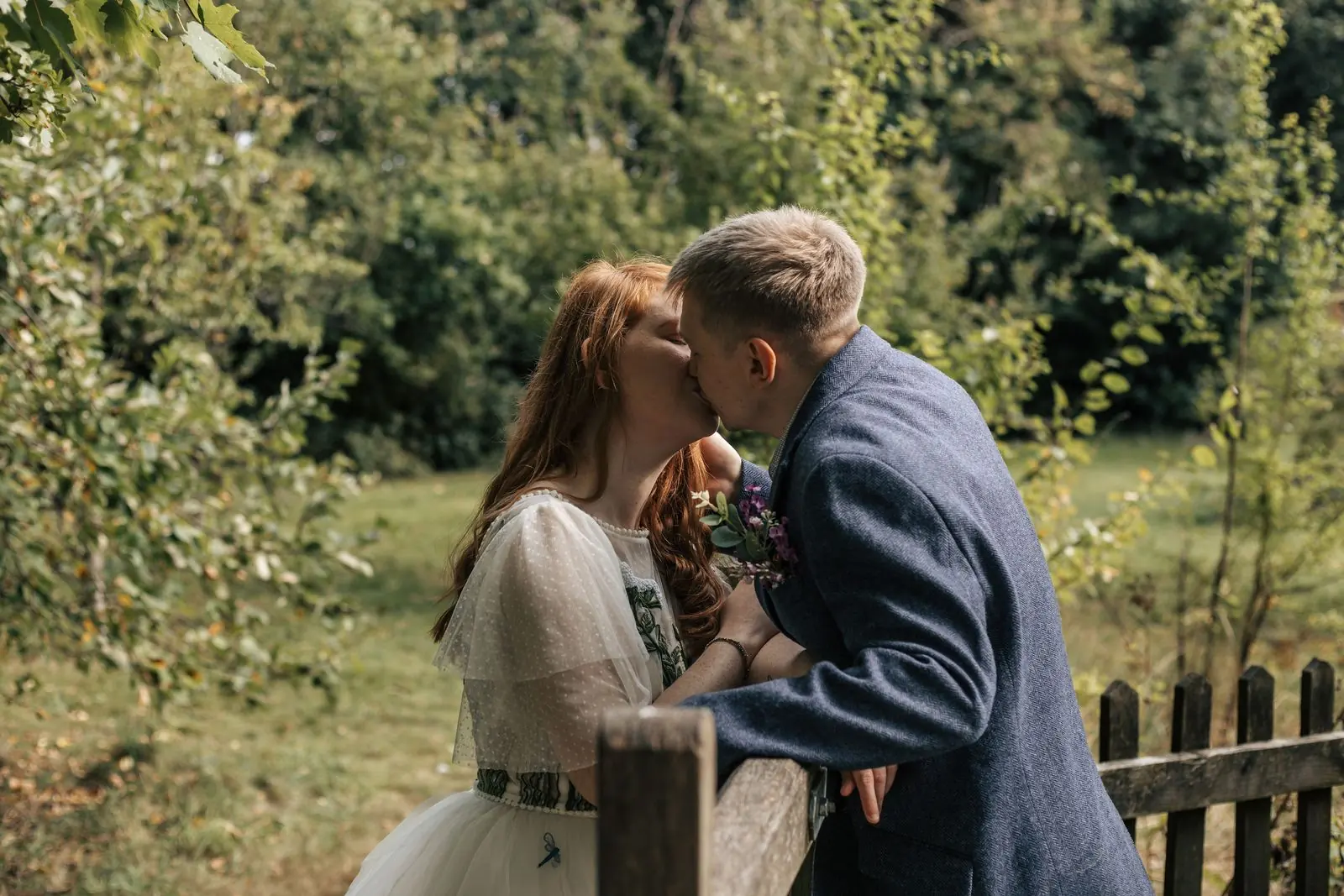 Couple kissing beside a wooden fence in the garden